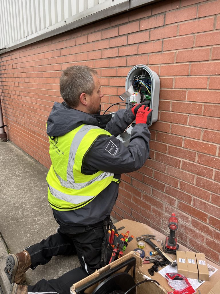 image of man installing ev charger to brick wall